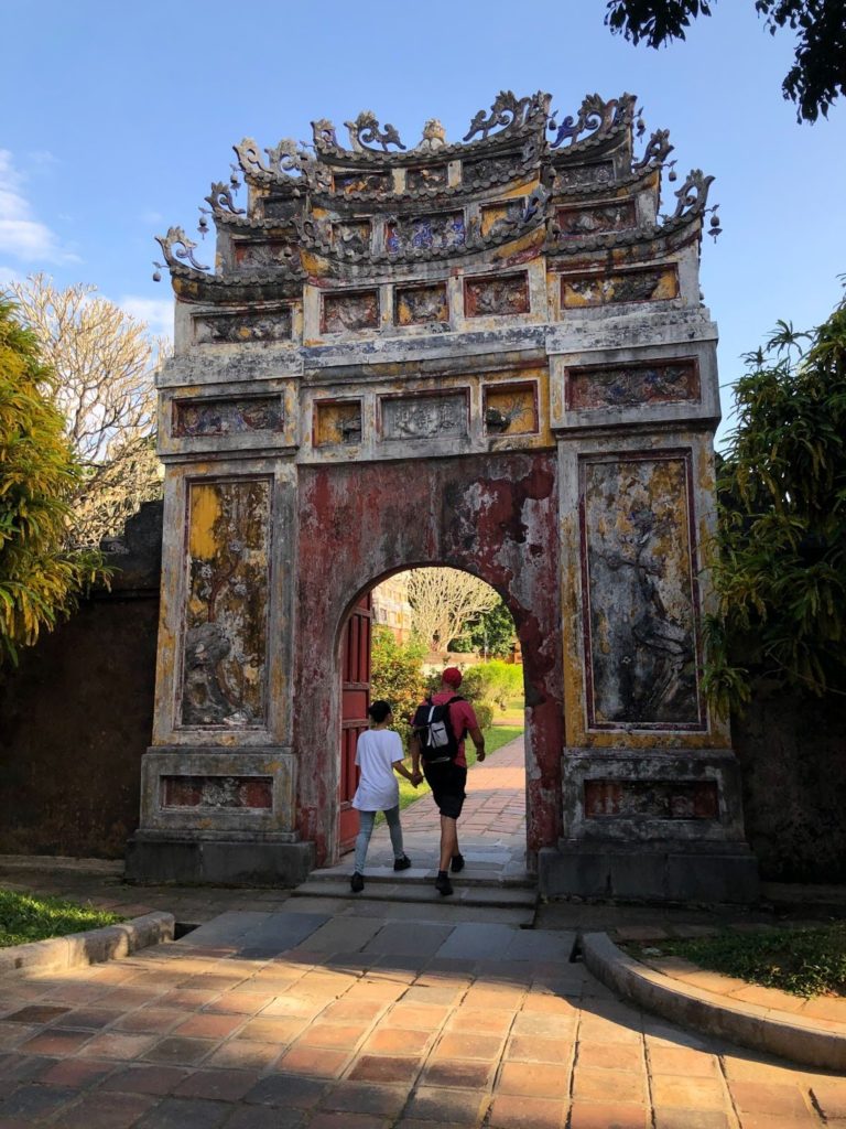 two tourist walking under old arch at hue imperial city